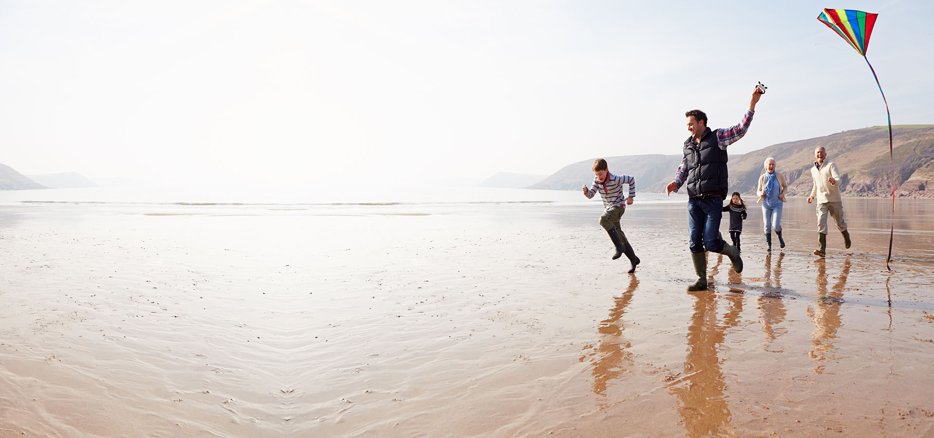 Family run on a beach with kite